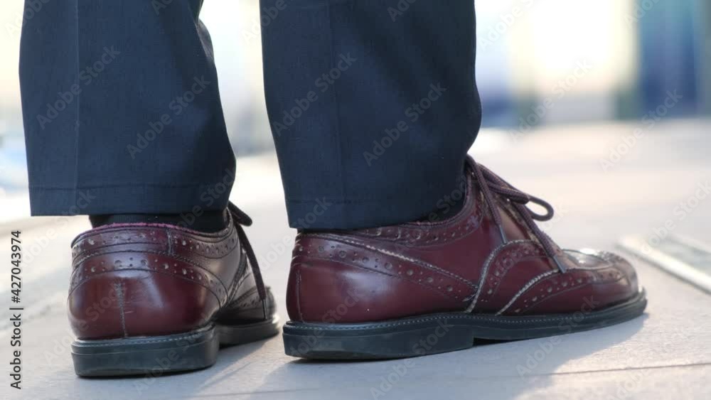 Legs of a worried, waiting man, tapping his shoes on the sidewalk Legs of a worried, waiting man, tapping his shoes on the sidewalk