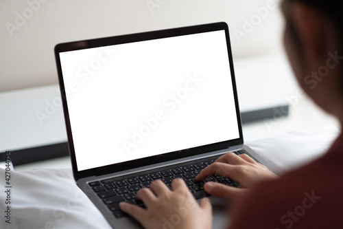 Woman working on laptop with white screen in bedroom at home