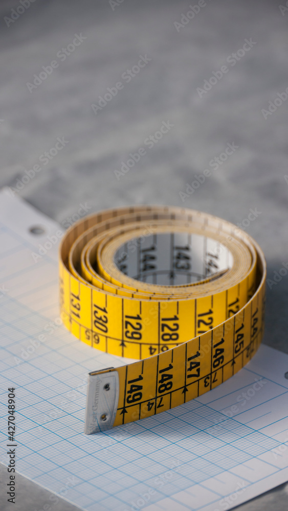 Cinta métrica amarilla y blanca enrollada sobre papel milimetrado Stock  Photo | Adobe Stock