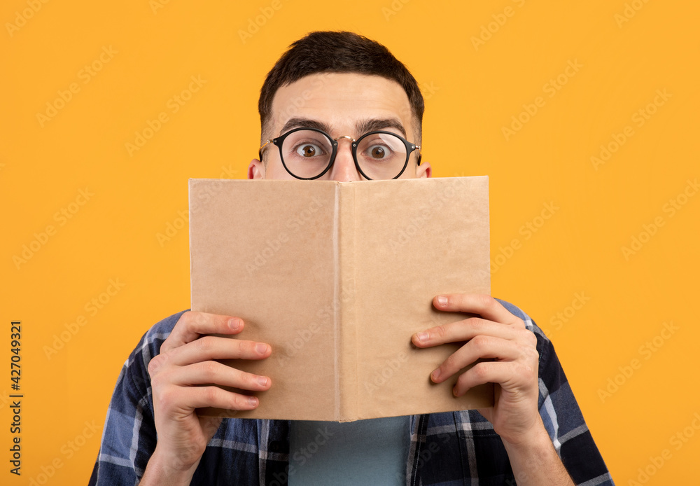 Ταπετσαρία Shocked young guy in glasses hiding behind book, having problem studying for col