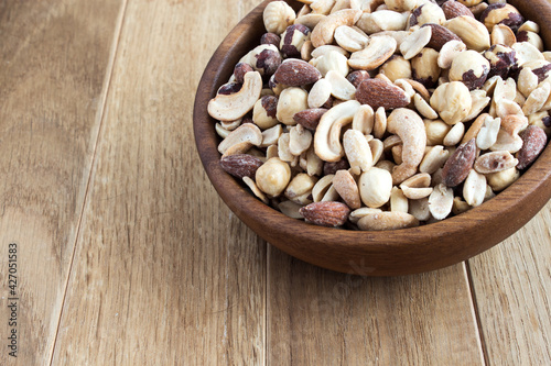 Salted nuts. Salted nuts cocktail on a wooden background. Mix of nuts in a wooden bowl. Copy space.