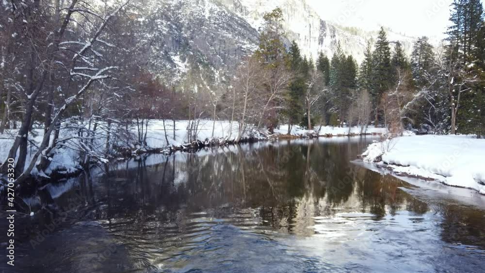 Slow pan over the river at Yosemite National Park with trees covered in snow during a cold winter day. Slow pan over the river at Yosemite National Park with trees covered in snow during a cold winter day.