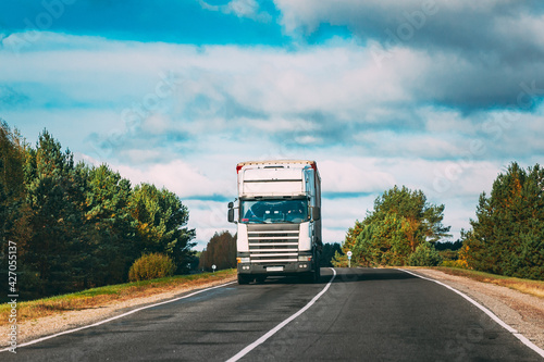 White Truck Or Tractor Unit, Prime Mover, Traction Unit In Motion On Summer Road, Freeway. Asphalt Motorway Highway During Sunny Day. Business Transportation And Trucking Industry Concept.