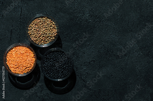 Red, black, brown seeds of dry lentils on dark background photo