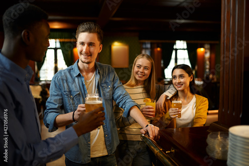Friends with beer make a toast at counter in bar