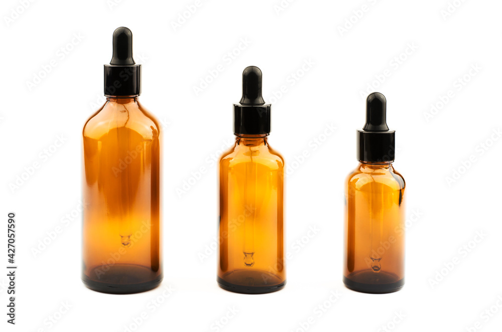 Three brown bottles with a dropper of different sizes for essential oils on a white background, isolate
