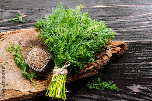 Fotografering Dry seeds with raw dill on wooden background