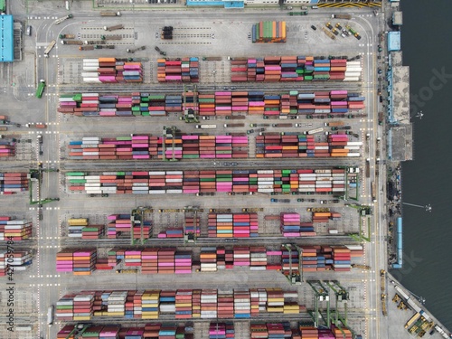 Aerial view of Container ship loading and unloading in deep sea port, import and export freight transportation by container ship in open sea with noise cloud. Jakarta, Indonesia, April 12, 2021