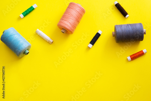Multi-colored reels with threads on a bright, colorful background. Top View
