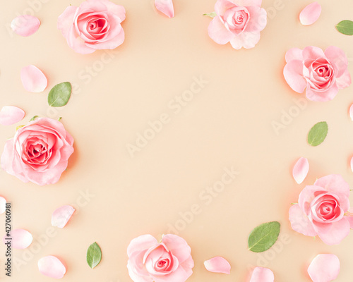 Pink rose, petals, leaves arranged on a golden background and a message space in the middle © Jelena