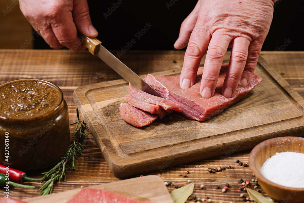 Man hands chop fresh raw meat steaks close up