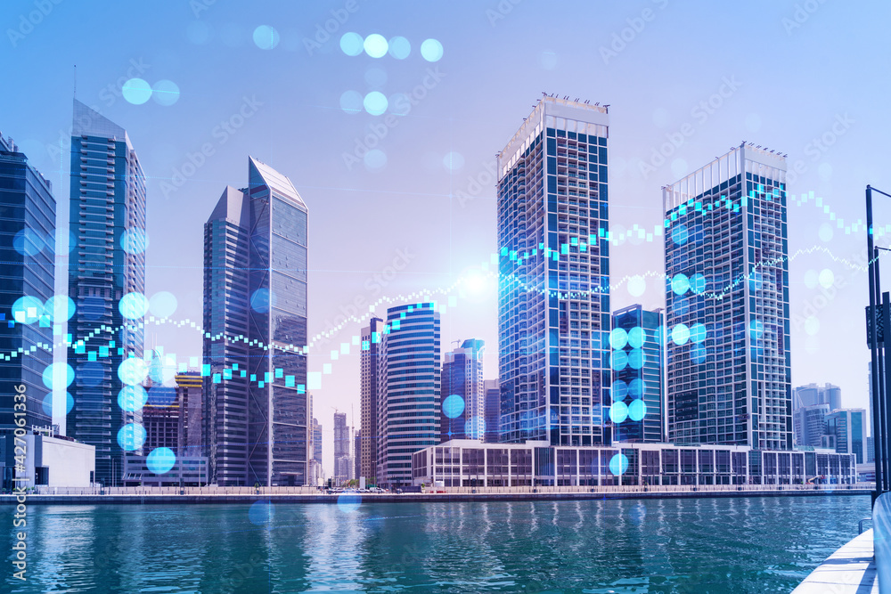 Fototapeta premium Skyscrapers of Dubai business downtown. International hub of trading and financial services of Western Asia. FOREX graph and chart concept. Double exposure. Dubai Canal waterfront.
