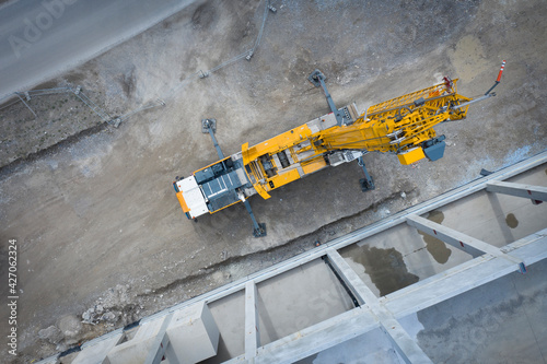 View from above on large heavy truck crane in front of concrete scaffolding of an industrial hall © A2LE