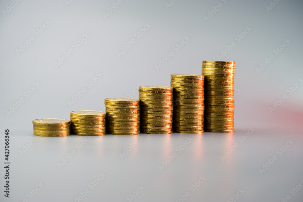Stacks of golden coins in ascending order on a light gray background. Stacks of golden coins in ascending order on a light gray background.