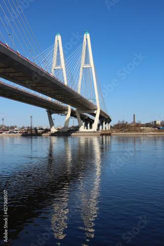 View of the cable-stayed bridge pylons and a fragment of the highway with reflexes in the water
