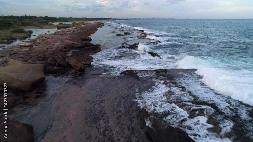Aerial view over rocks and waves on the coast of Playa Los Cuadritos beach, in San Cristobal - low, drone shot Aerial view over rocks and waves on the coast of Playa Los Cuadritos beach, in San Cristobal - low, drone shot