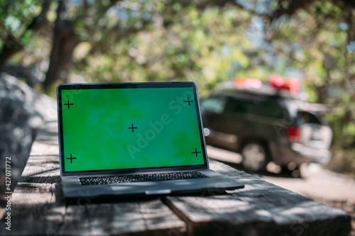 Open laptop on a wooden table in a camping in the mountains