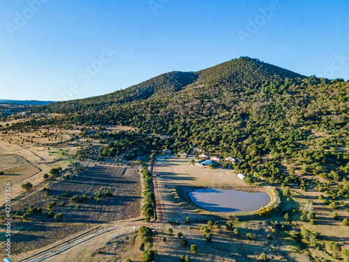 Fotografía aérea de cabañas junto a un lago en un bosque con un cielo despejado y una montaña en el fondo