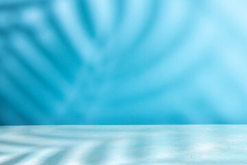 Palm coconut leaf shadow on table top and blue wall background. Abstract summer backdrop with copy space.