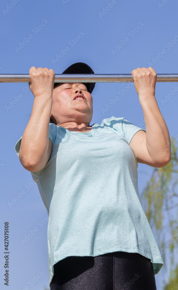 Naklejka premium Asian woman working out lifting a metal bar