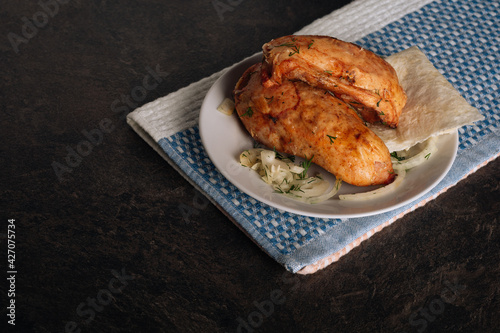 Delicious grilled chicken breasts on a plate on the dark background