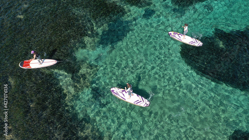 Aerial drone photo of fit women practice Stand Up Paddle or SUP in tropical exotic island shallow water emerald bay © aerial-drone