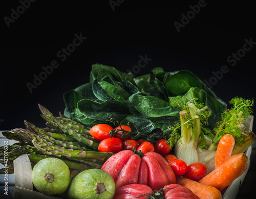 fresh and wet vegetables in the foreground on a black background. selective blur.