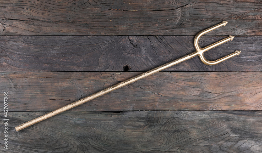 golden trident isolated on wooden background golden trident isolated on wooden background