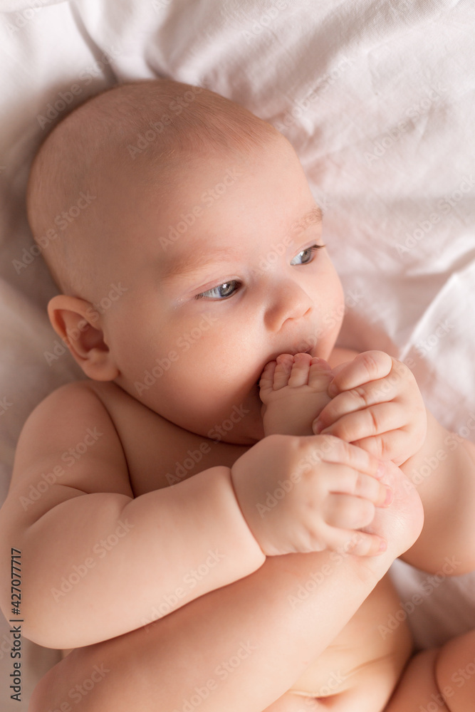 Cute baby in diapers lies in bed with white cotton linen, view from above, space for text Cute baby in diapers lies in bed with white cotton linen, view from above, space for text