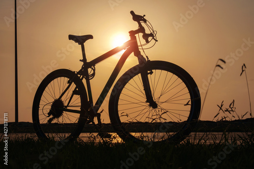 Silhouette of a bike at sunset. The sun shines through the bicycle frame at the coast