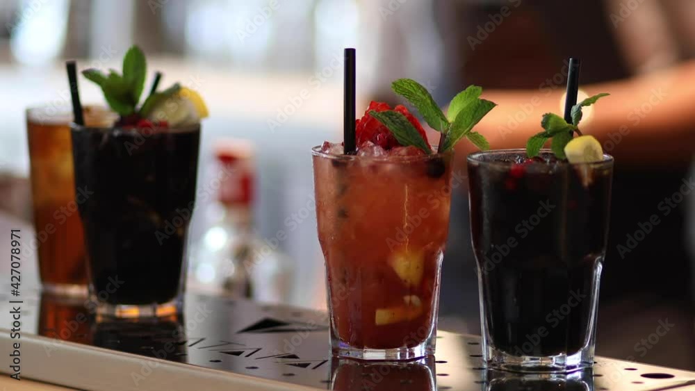 Cocktails with fruits and plastic straws in glasses stand on table in Cocktails with fruits and plastic straws in glasses stand on table in