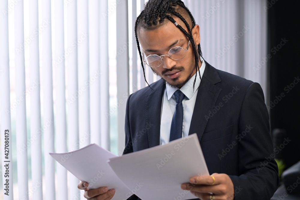 A young stylish black unusual office employee examines the received documents, carefully examines them. Young boss with an unusual appearance in the office A young stylish black unusual office employee examines the received documents, carefully examines them. Young boss with an unusual appearance in the office