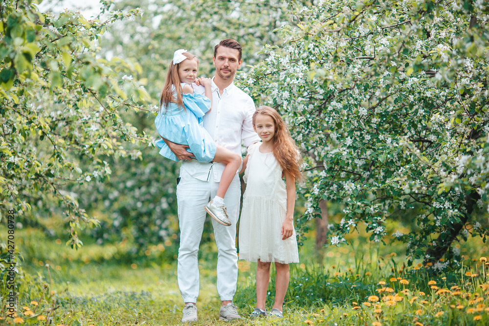 Adorable family in blooming cherry garden on beautiful spring day