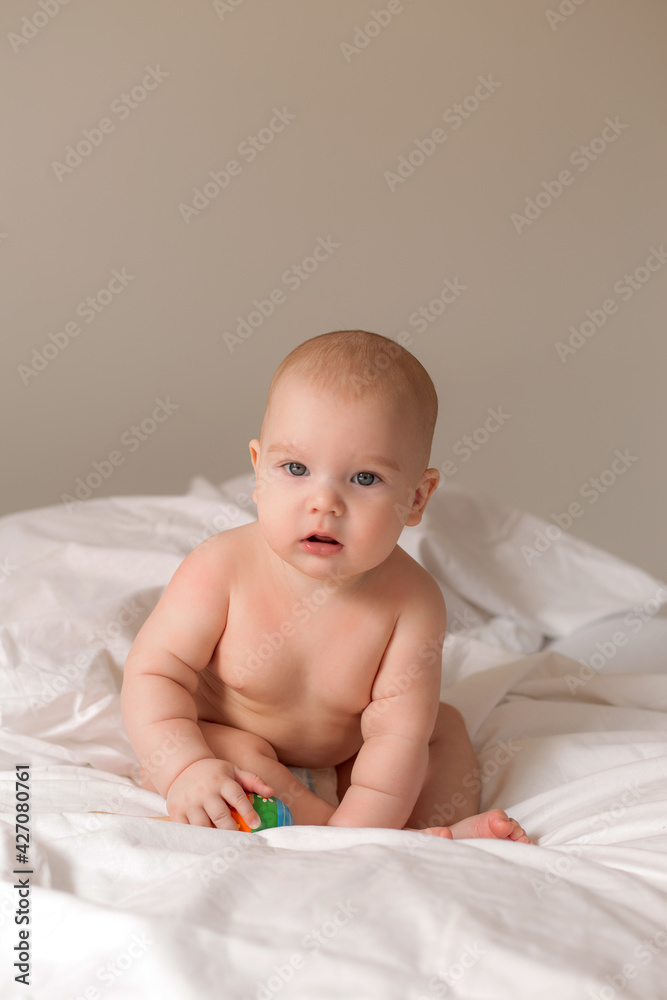 baby sitting in bed playing with wooden developing toy baby sitting in bed playing with wooden developing toy