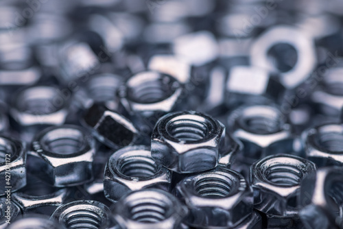 Close-up metal chrome nuts in a chaotic order. Background concept for fasteners and construction topics. Repair and spare parts concept