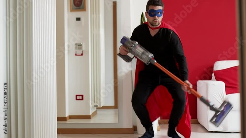 Man dressed as a superhero dances doing housecleaning.