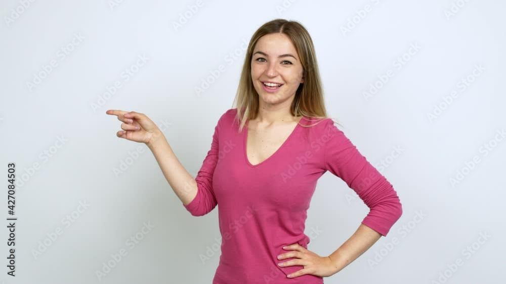 Young woman pointing to the side and presenting a product while smiling over isolated background Young woman pointing to the side and presenting a product while smiling over isolated background