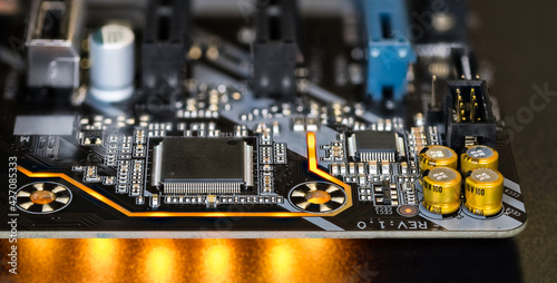 Printed circuit board on modern computer motherboard detail with electronic components. Micro chips, capacitors or resistors and yellow LED light effects on black background. Surface-mount technology. photo