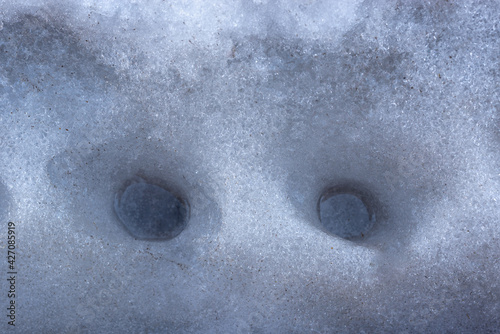 The water droplets made holes in the snow and ice.