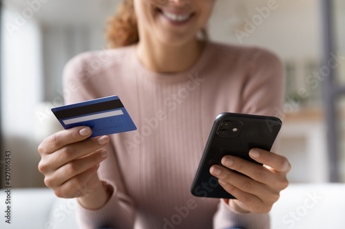 Online shopper. Close up of happy millennial female satisfied bank web shop customer buying paying easy from home. Focus on woman hands typing data from credit card in banking app on cellphone screen