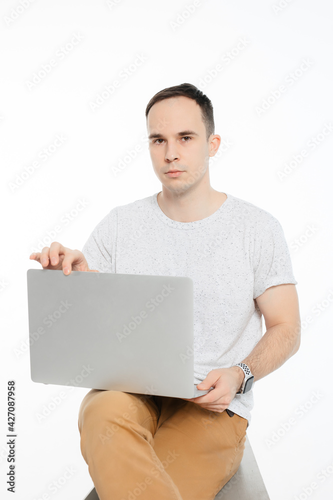 a man sits and holds an open computer on a white background a man sits and holds an open computer on a white background