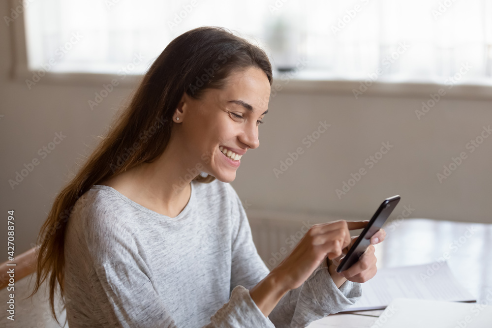 Happy millennial Latin woman hold use modern cellphone gadget text or message online on cell. Smiling young female look at smartphone screen, browse internet on device. Technology concept. Happy millennial Latin woman hold use modern cellphone gadget text or message online on cell. Smiling young female look at smartphone screen, browse internet on device. Technology concept.