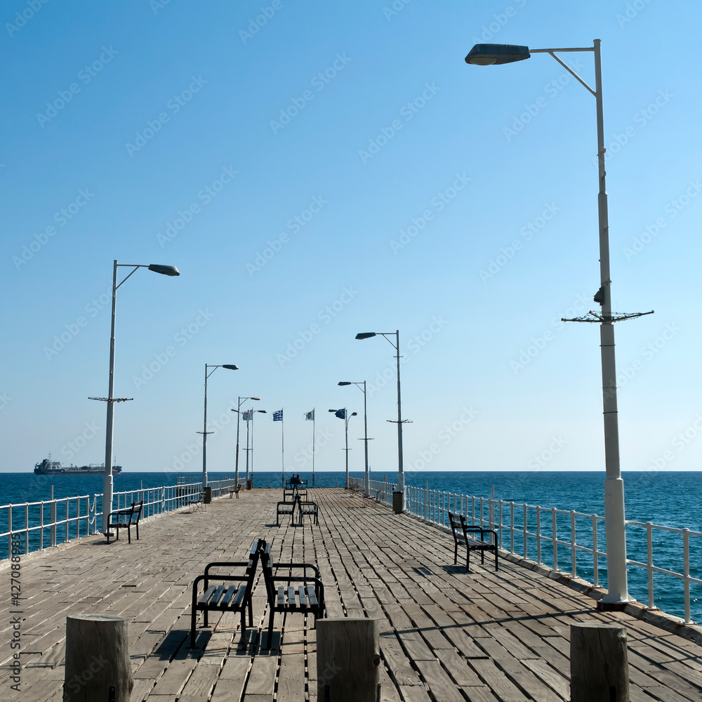 Sea pier with benches, street lamps and flags