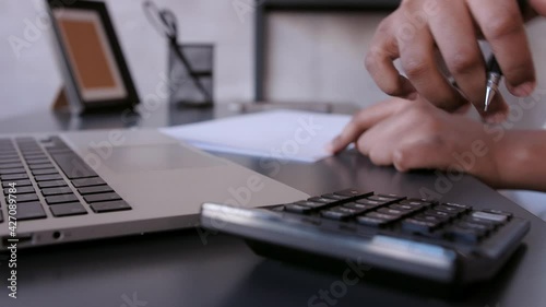  black business woman counts on a calculator and makes notes. financier or accountant works from home