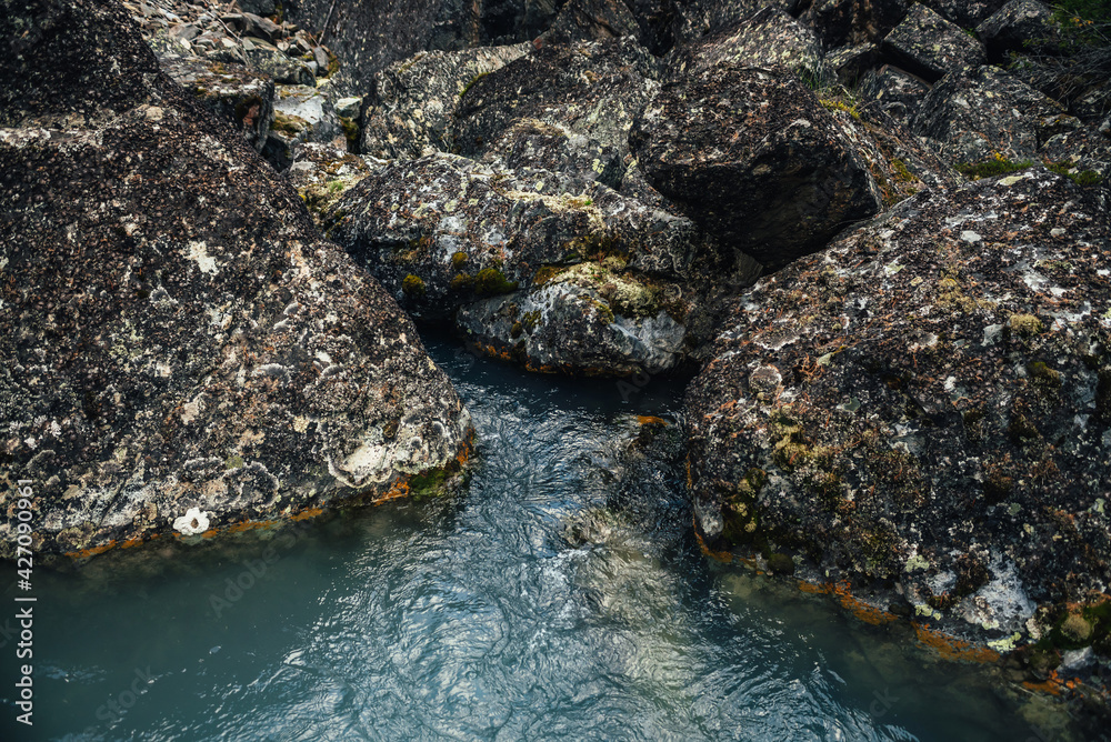 Scenic nature background of turquoise clear water stream among rocks with mosses and lichens. Atmospheric mountain landscape with mossy stones in transparent mountain creek. Beautiful mountain stream. Scenic nature background of turquoise clear water stream among rocks with mosses and lichens. Atmospheric mountain landscape with mossy stones in transparent mountain creek. Beautiful mountain stream.
