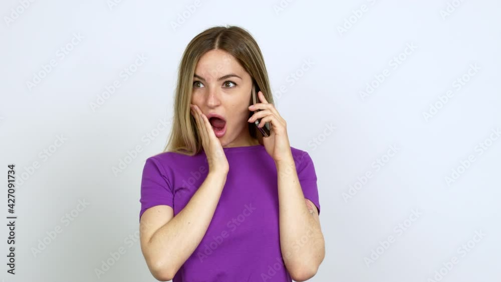 Young woman talking on mobile phone gaping because have just surprised with a gift over isolated background Young woman talking on mobile phone gaping because have just surprised with a gift over isolated background