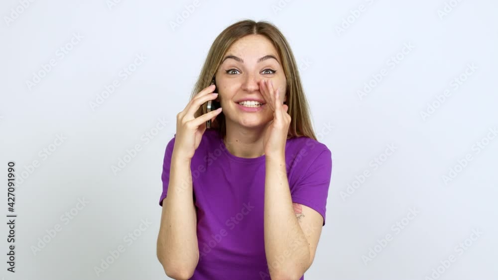 Young woman talking on mobile phone shouting and announcing something over isolated background Young woman talking on mobile phone shouting and announcing something over isolated background