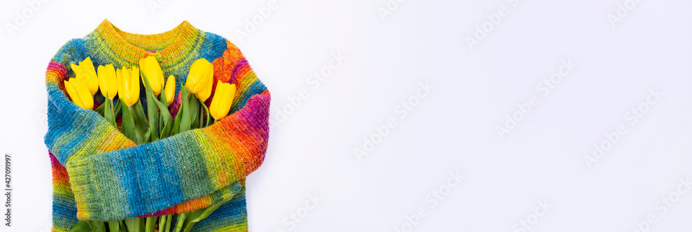 Bouquet of yellow tulips on the background of a multicolored knitted sweater, top view, bouquet of yellow tulips for women's day, spring flowers concept