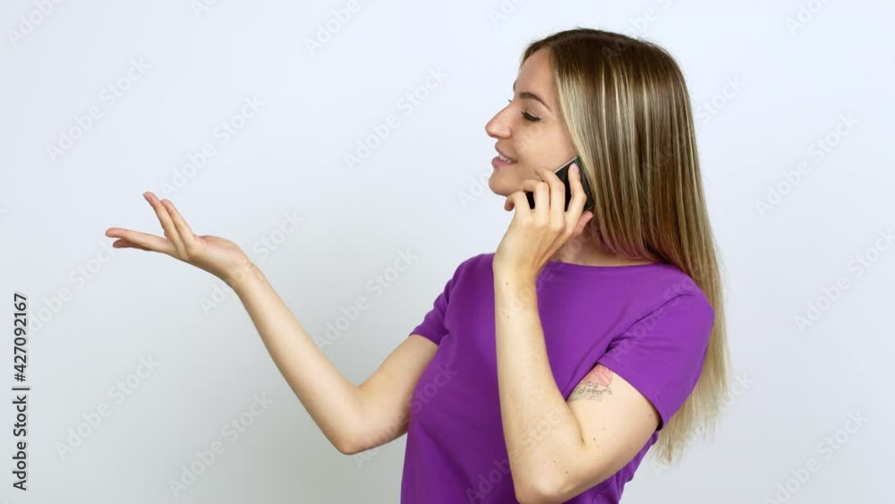 Young woman talking on mobile phone extending hands to the side and inviting to come over isolated background Young woman talking on mobile phone extending hands to the side and inviting to come over isolated background