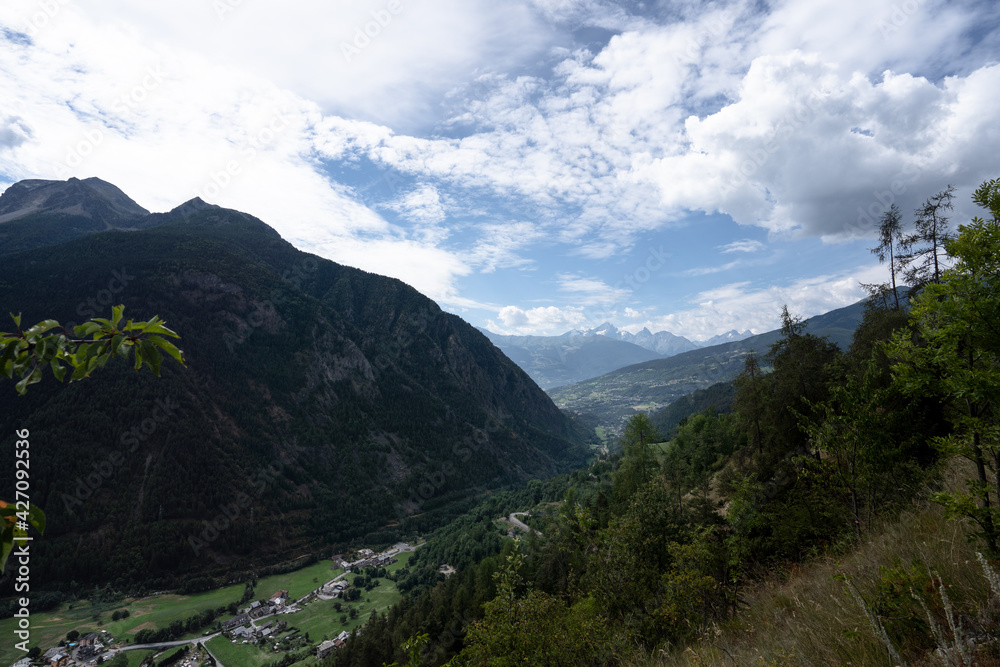 View of the valley from Doues, Valpelline. Mountains, trees, cloudy sky. Villages in the distance.